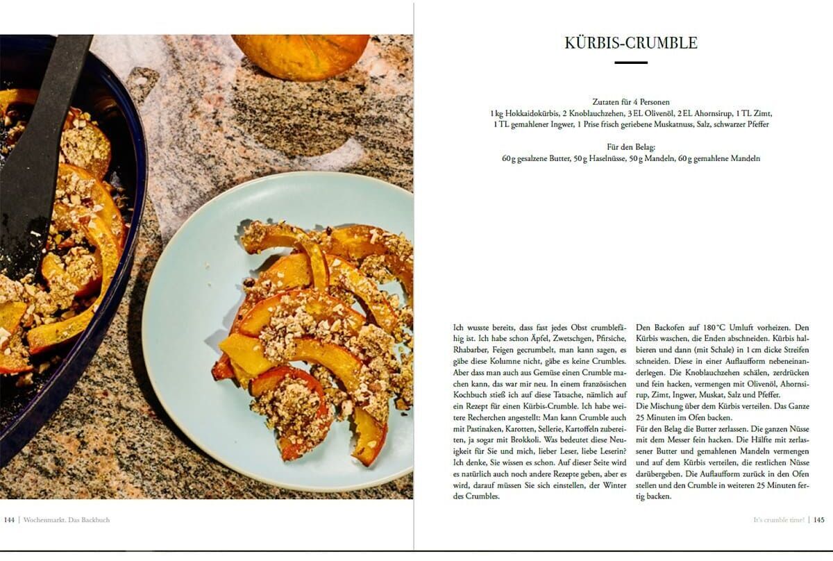 Eine offene Doppelseite des »Wochenmarkt-Backbuchs« zeigt ein Rezept für Kürbis-Crumble. Links ist ein schräg angeschnittener Teller mit einem Stück Crumble auf einem blauen Teller, daneben ein schwarzer Spatel. Die Seite rechts enthält detaillierte Anweisungen und Zutaten für die Zubereitung des Rezepts.