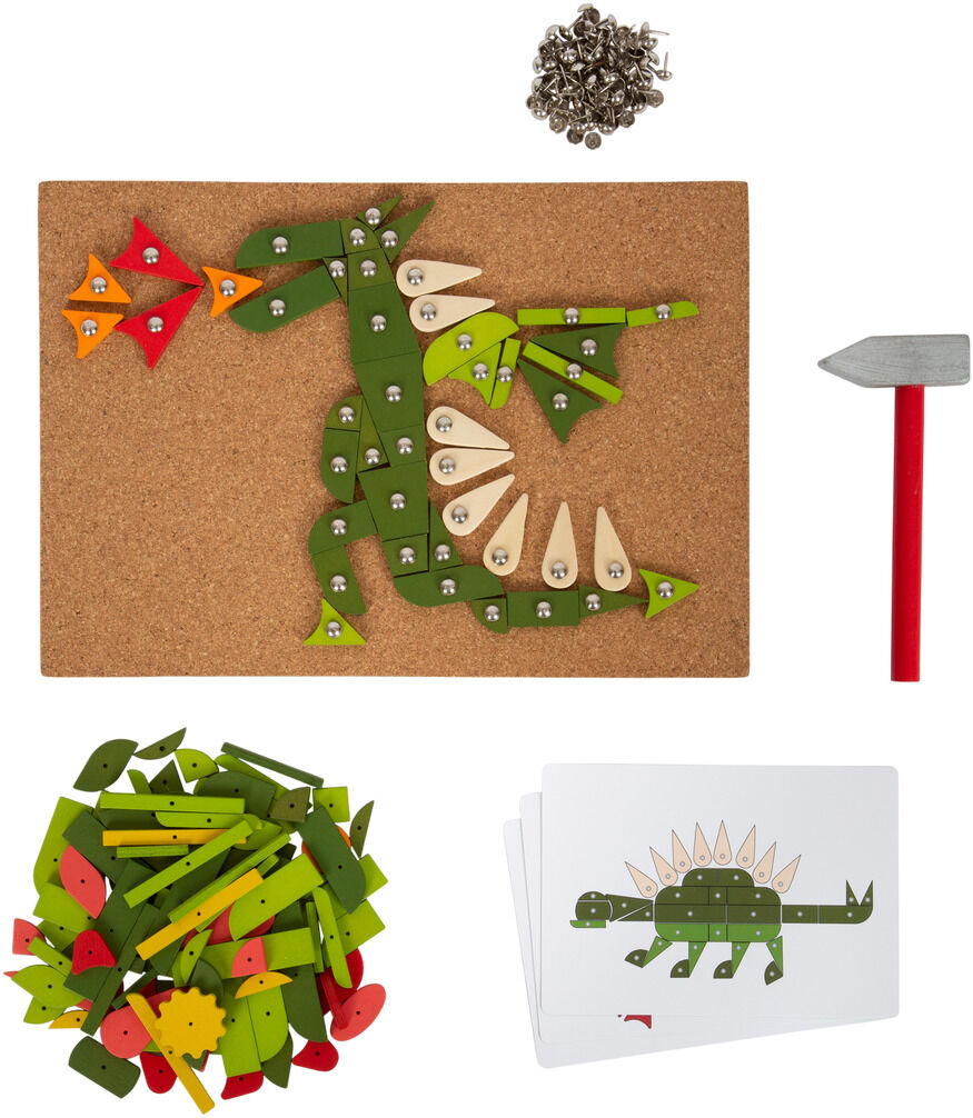 Spielset mit Korkunterlage, grünen und roten Holzformen, silbernen Nägeln, rotem Hammer und Karten mit Drachenmotiven.