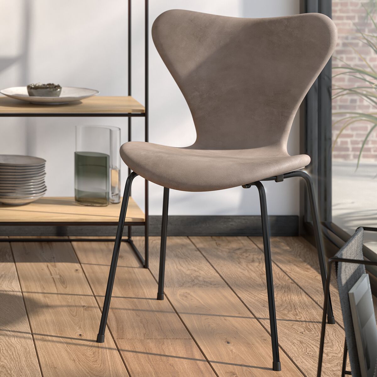 Design-Esszimmerstuhl Modell »3107« von Arne Jacobsen, beigefarbene Sitzschale mit schwarzen Metallbeinen, vor Tageslicht-Fenster arrangiert, moderner und minimalistischer Wohnraum mit Holzregal und Geschirr im Hintergrund.