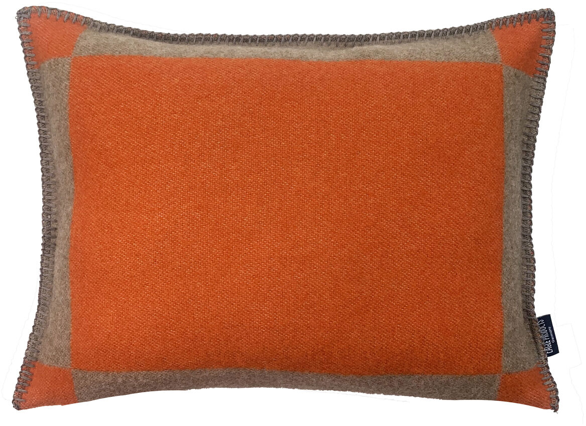 Eine rechteckige Kissenhülle »Manchester« in orange mit braunen Akzenten und gehäkelten Kanten.