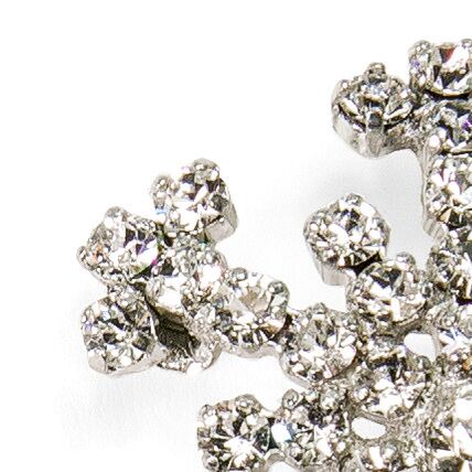 Detailaufnahme einer glitzernden Brosche in Form einer Schneeflocke mit funkelnden Kristallsteinen, silberfarben, weihnachtliches Schmuckstück als festliches Accessoire.