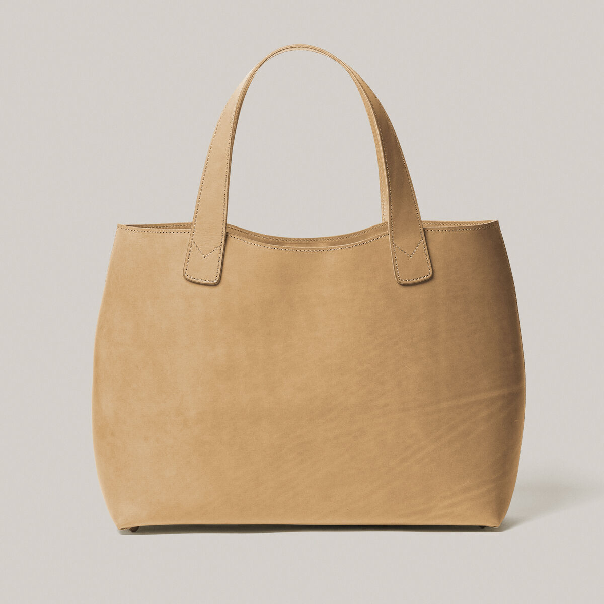 Große Tasche aus Kernleder in Beige mit zwei Henkeln, vor einem weißen Hintergrund. Perfekt geeignet für Alltagsaktivitäten und als elegantes Modeaccessoire.