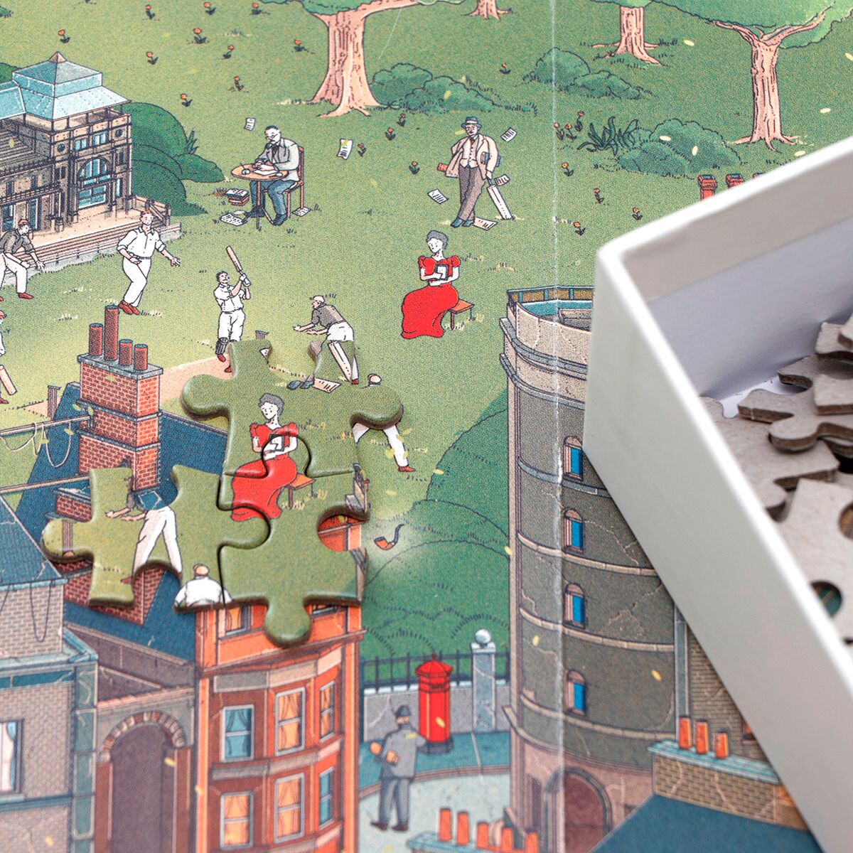 Das Bild zeigt ein detailreiches Puzzle mit einer farbigen Illustration von Shakespeares London, darauf Menschen in historischer Kleidung, Bäume und typische Bauten. Mehrere Puzzleteile fehlen noch, die Kanten sind sichtbar. Rechts oben befindet sich eine weiße Puzzlebox mit weiteren Teilen.