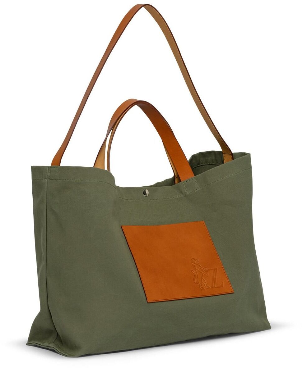 Eine grüne Jubiläums-Markttasche mit braunen Ledergriffen und Lederaufnähern. Die Tasche ist geräumig und robust, ideal für den Einkauf und den alltäglichen Gebrauch.