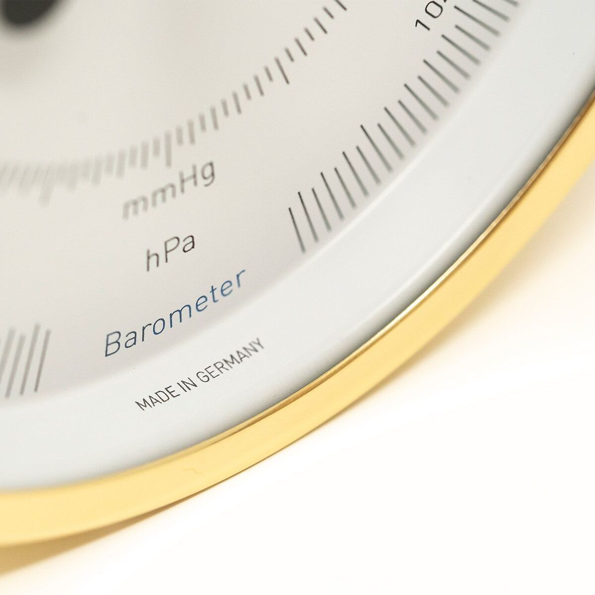 Nahaufnahme eines Barometers mit Anzeigen in hPa und mmHg, umgeben von einem goldfarbenen Rahmen. Unten ist der Schriftzug 'Made in Germany' zu sehen.