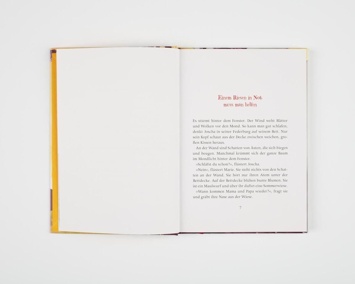 Ein aufgeschlagenes Buch mit dem Titel 'Wir sind nachher wieder da, wir müssen kurz nach Afrika', dessen Seite weiß ist und schwarz-roten Text enthält. Der Umschlag hat eine gelbe Innenseite.