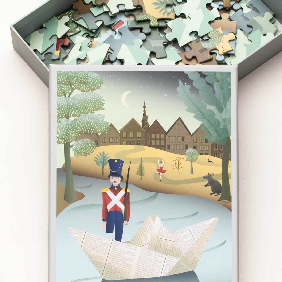 Puzzle mit 100 Teilen zeigt eine Illustration zum Märchen 'Der standfeste Zinnsoldat': Ein Zinnsoldat steht auf einem Papierboot auf einem stillen Fluss vor einer abendlichen Dorflandschaft mit Bäumen, Häusern, einer Tänzerin und Tieren im Hintergrund. Die Szene ist in sanften Pastellfarben gehalten.