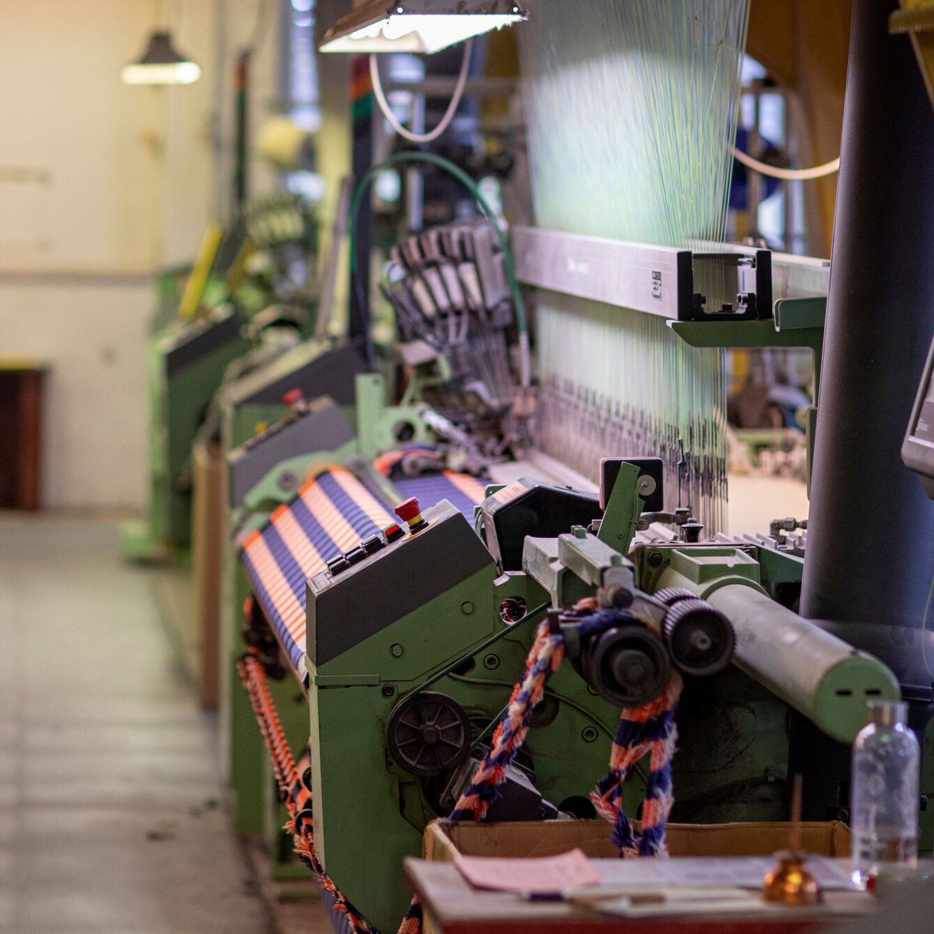 Industrielle Webmaschine mit bunten Garnen in einer Textilfabrik