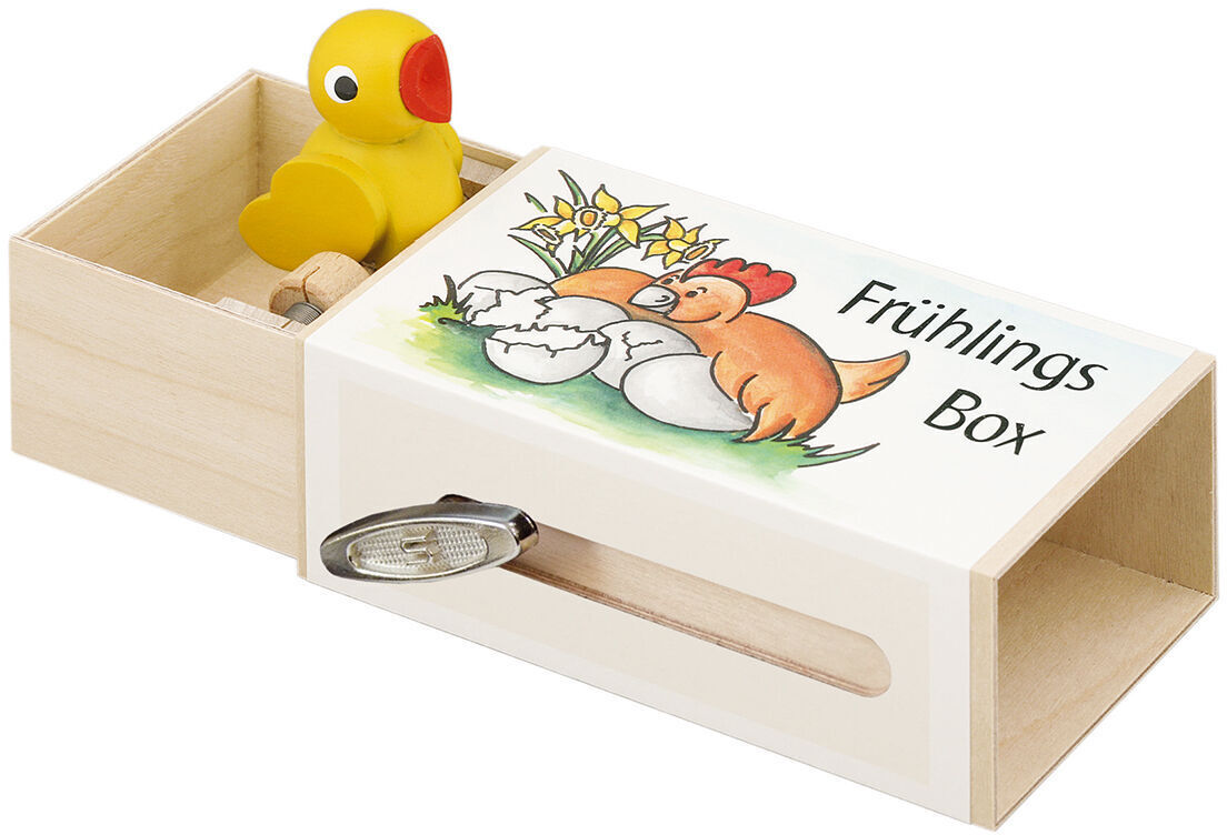Musikalische Frühlingsbox aus Holz mit einer gelben Ente auf einem Schiebefach und einer Illustration mit Blumen und einem Küken. Die Box trägt die Aufschrift 'Frühlings Box'.