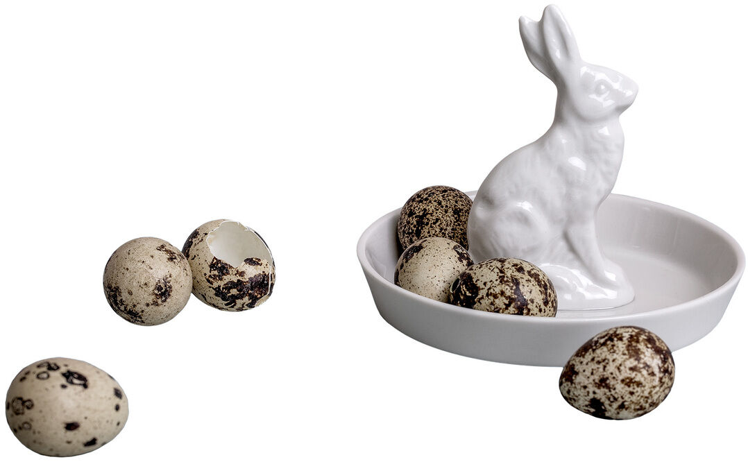 Ein weißer Porzellanteller mit einer sitzenden Hasenfigur und mehreren dekorativen, gefleckten Ostereiern. Das Geschirrstück eignet sich perfekt als Osterdekoration.