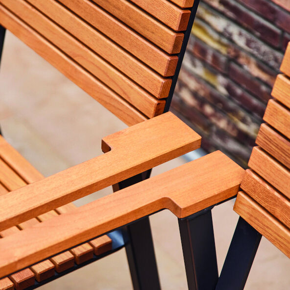 Nahaufnahme eines modernen Stapelsessels mit Holzlatten und schwarzem Metallrahmen. Das Produkt eignet sich hervorragend für Outdoor- und Innenbereiche.