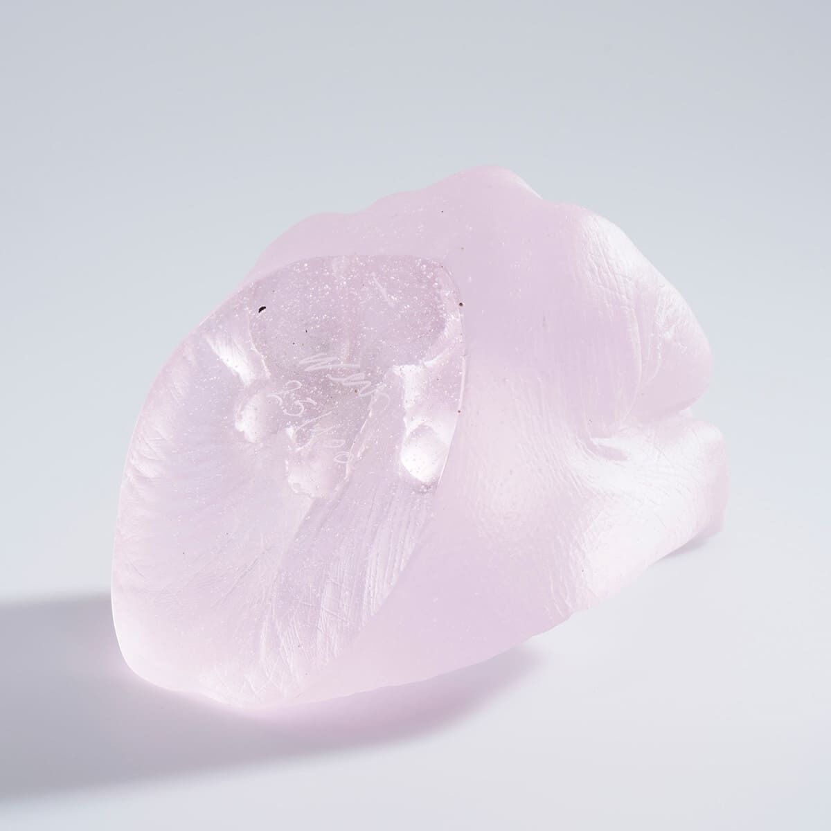 Eine Skulptur aus hellrosafarbenem Glas von Ai Weiwei, die einen Finger in personaler Perspektive darstellt, auf einem einfachen, weißen Hintergrund.