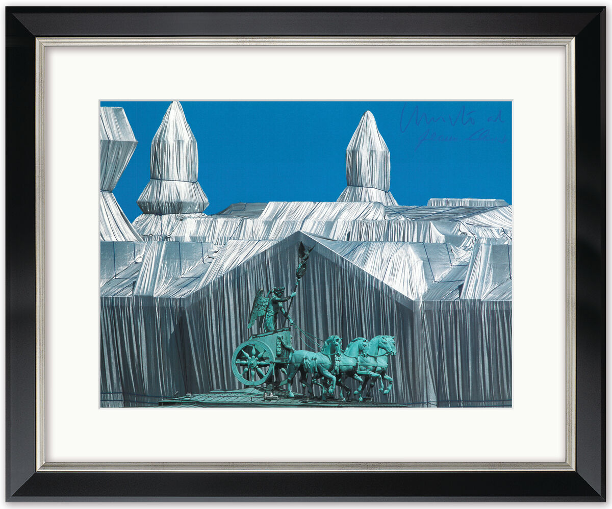 Fotografie des verhüllten 'Reichstag mit Quadriga' von Christo und Jeanne-Claude, das den verhüllten Berliner Reichstag mit der Quadriga auf dem Dach unter blauem Himmel zeigt. Das Bild ist in einem schwarzen Rahmen mit weißem Passepartout präsentiert.