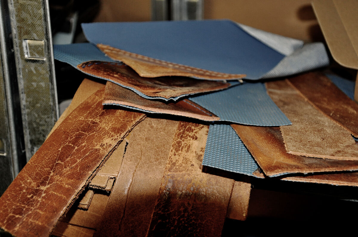 Stapel von Leder- und Stoffstücken in verschiedenen Brauntönen und Blau. Hochwertiges Material für die Herstellung der exklusiven ZEIT-Tasche in Kastenform.