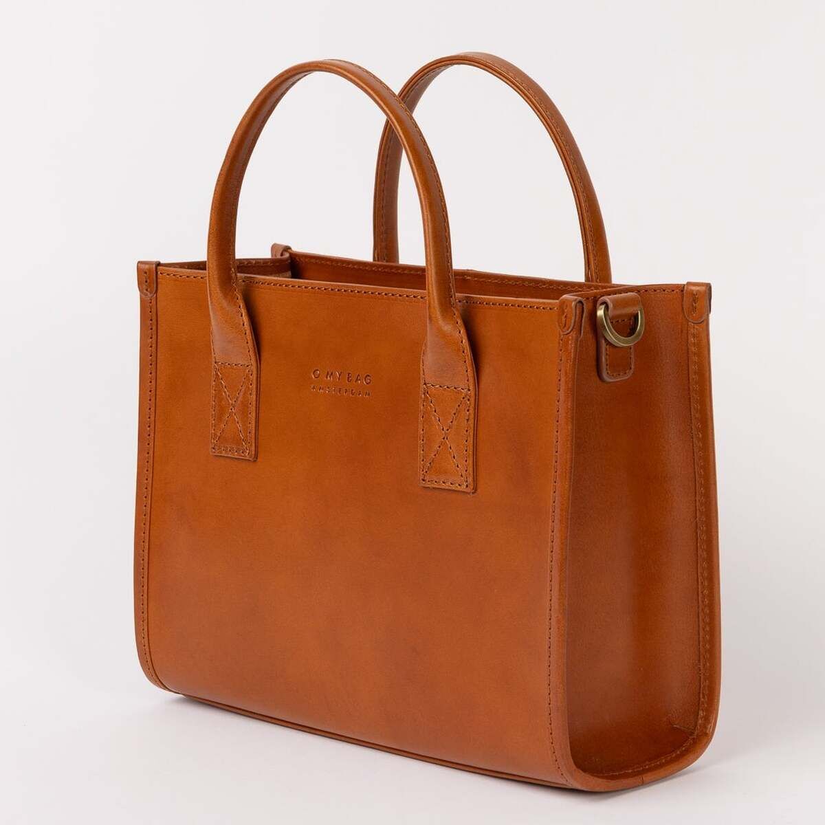 Braune Ledertasche Jackie Midi mit zwei Henkeln im minimalistischen Design, stehend auf hellem Hintergrund, geeignet für Beruf und Alltag.