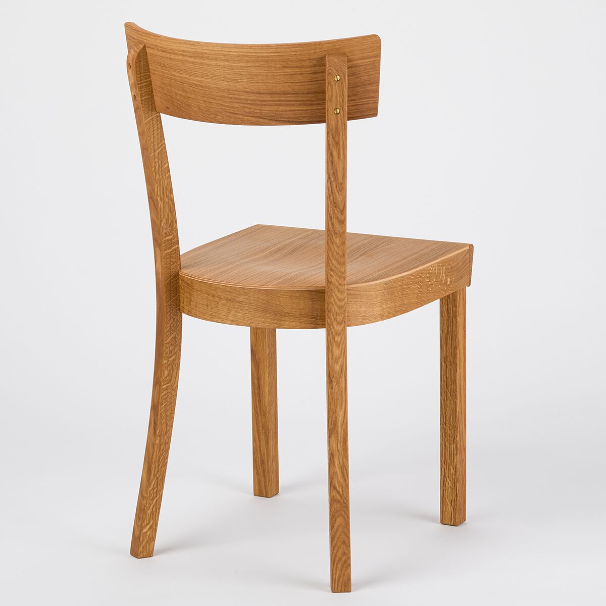 Ein schlichter, moderner Stuhl aus geölter Eiche mit geschwungener Rückenlehne. Der Frankfurter Küchenstuhl steht frei vor weißem Hintergrund und zeigt seine klare Linienführung und hochwertige Verarbeitung.