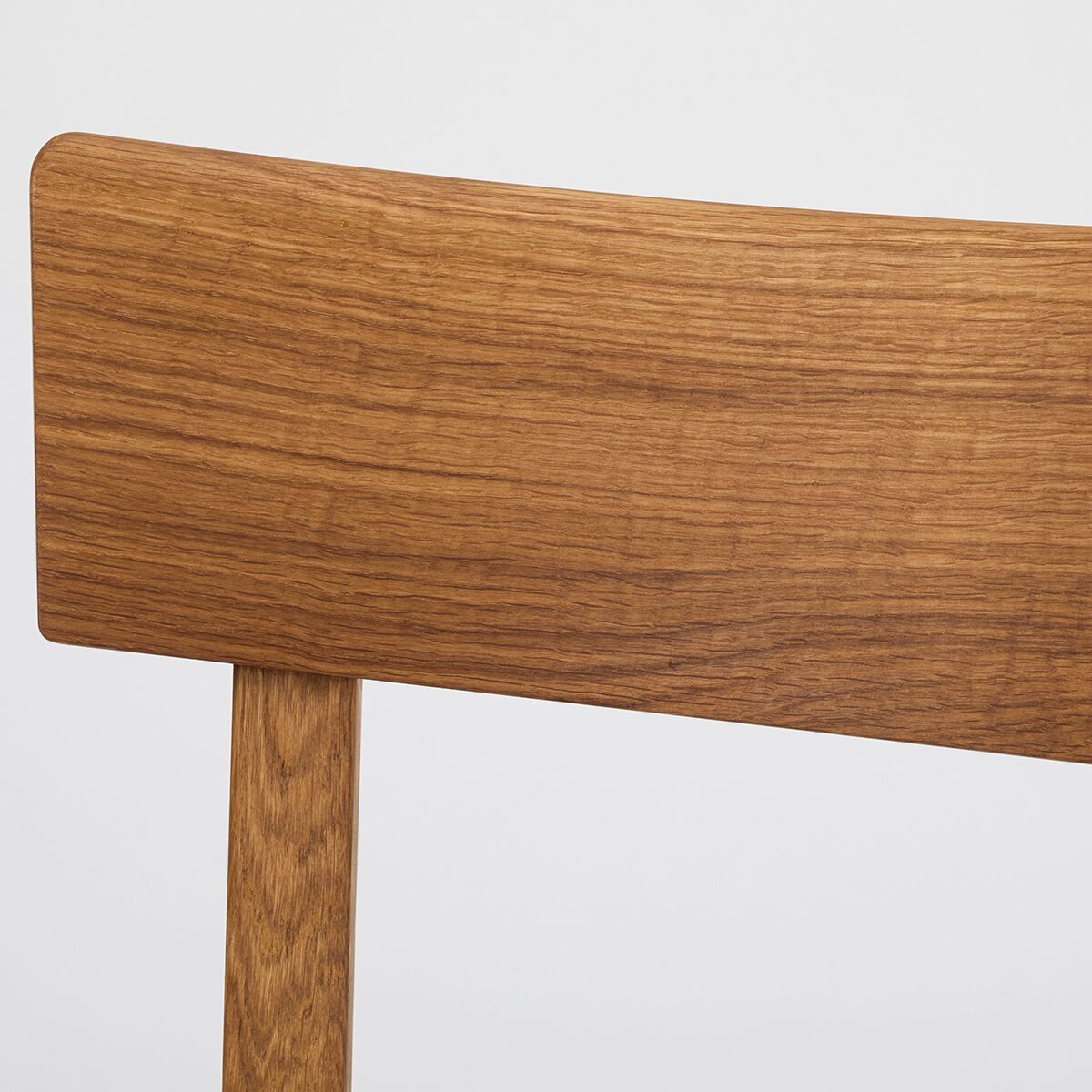 Detailansicht einer Rückenlehne des Küchenstuhls ZEIT Sonderedition »Frankfurter Küchenstuhl« aus geölter Eiche, minimalistisches Design, naturbelassene Holzoberfläche mit sichtbarer Maserung, robust und modern.
