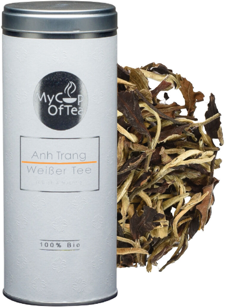 Eine weiße Tee-Dose mit der Aufschrift 'Anh Trang Weißer Tee' und getrockneten Teeblättern daneben. Die Dose trägt ein Etikett mit der Aufschrift '100% Bio'.