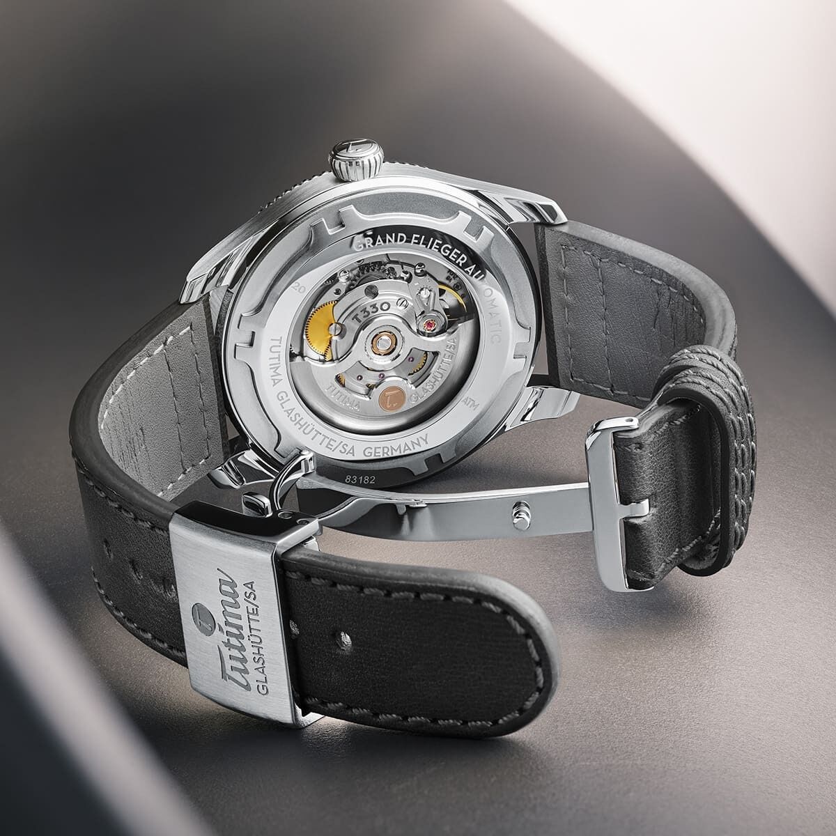 Rückansicht der ZEIT-Sonderedition »Grand Flieger Classic Automatic Schiefergrau« Uhr, die ein Edelstahlgehäuse, ein Lederarmband und einen sichtbaren Rotor zeigt.