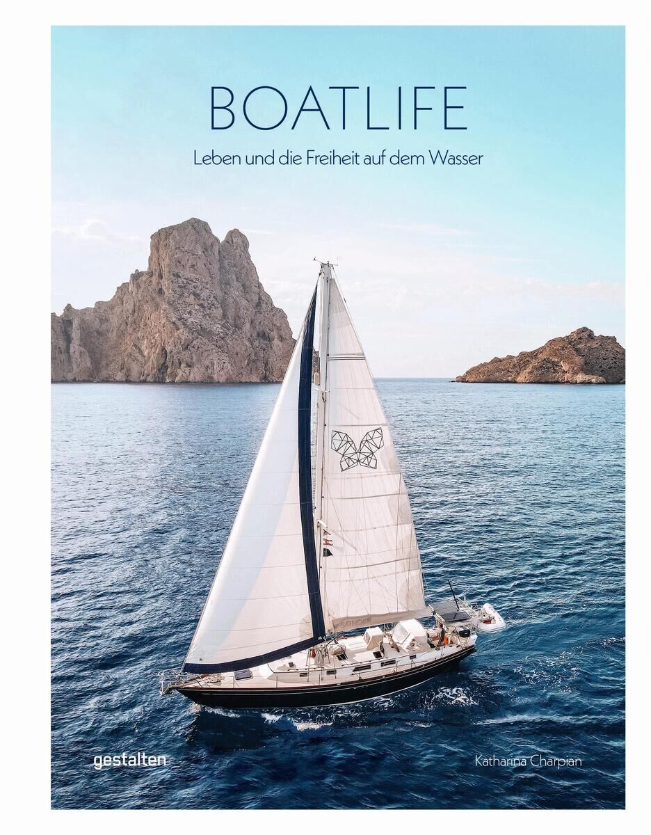 Ein Segelboot segelt auf dem blauen Meer, mit einer felsigen Küste im Hintergrund und einem blauen Himmel. Auf dem Segel des Boots ist ein Schmetterling abgebildet. Der Titel des Buches lautet 'Boatlife', darunter der Text 'Leben und die Freiheit auf dem Wasser'.