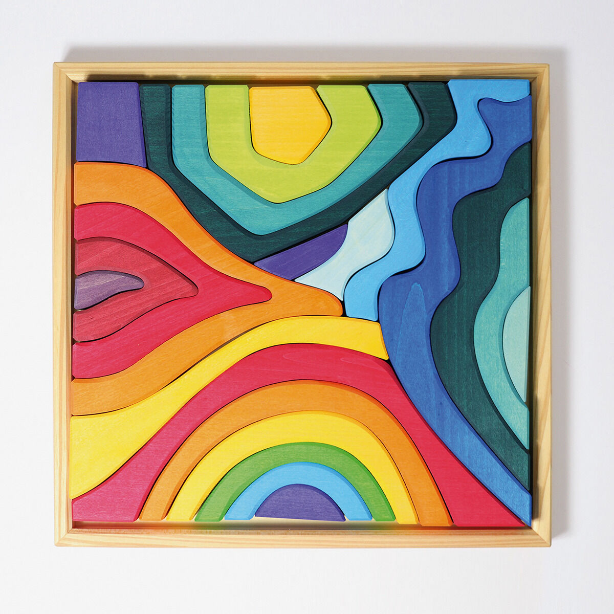 Bausatz aus Holz in Form einer abstrakten Landschaft mit verschiedenen geschwungenen Teilen in bunten Farben, eingerahmt von einem Holzrahmen.