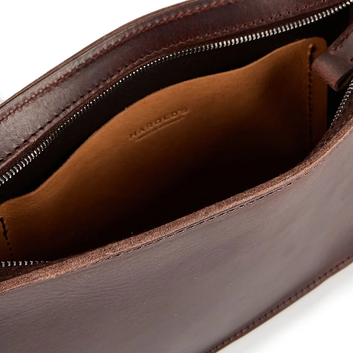 Nahaufnahme der geöffneten Kernledertasche »Sas« in Dunkelbraun von Harold's Lederwaren, zeigt das Hauptfach mit Reißverschluss, glattes, pflanzlich gegerbtes Sattlerleder, Innenfach mit sichtbarer Prägung des Markennamens, hochwertige Verarbeitung, dezentes Design.