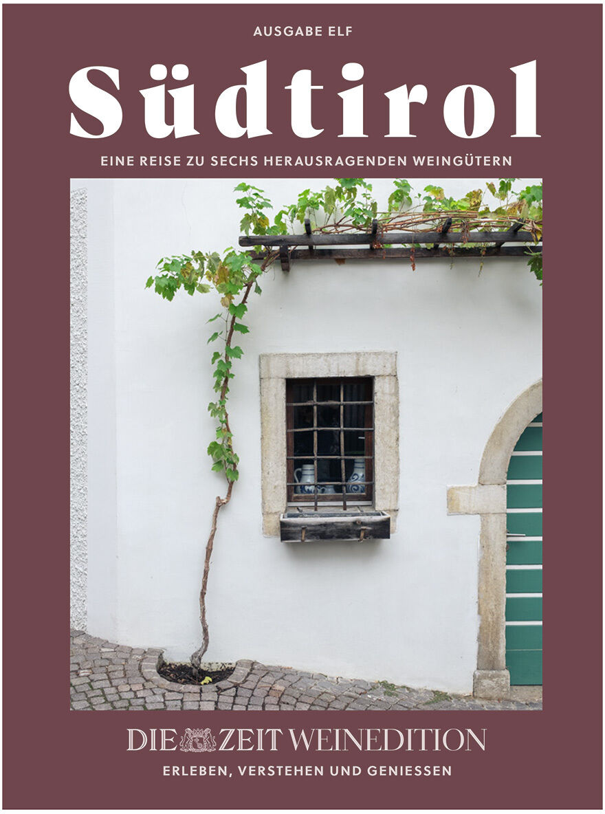 Titelblatt des Magazins „Südtirol – Eine Reise zu sechs herausragenden Weingütern“. Darauf abgebildet ist eine weiß verputzte Hauswand mit Fenster, Weinranke und Kopfsteinpflaster, eingerahmt von einem dunkelroten Rand. Im unteren Bereich das Logo der ZEIT Weinedition.