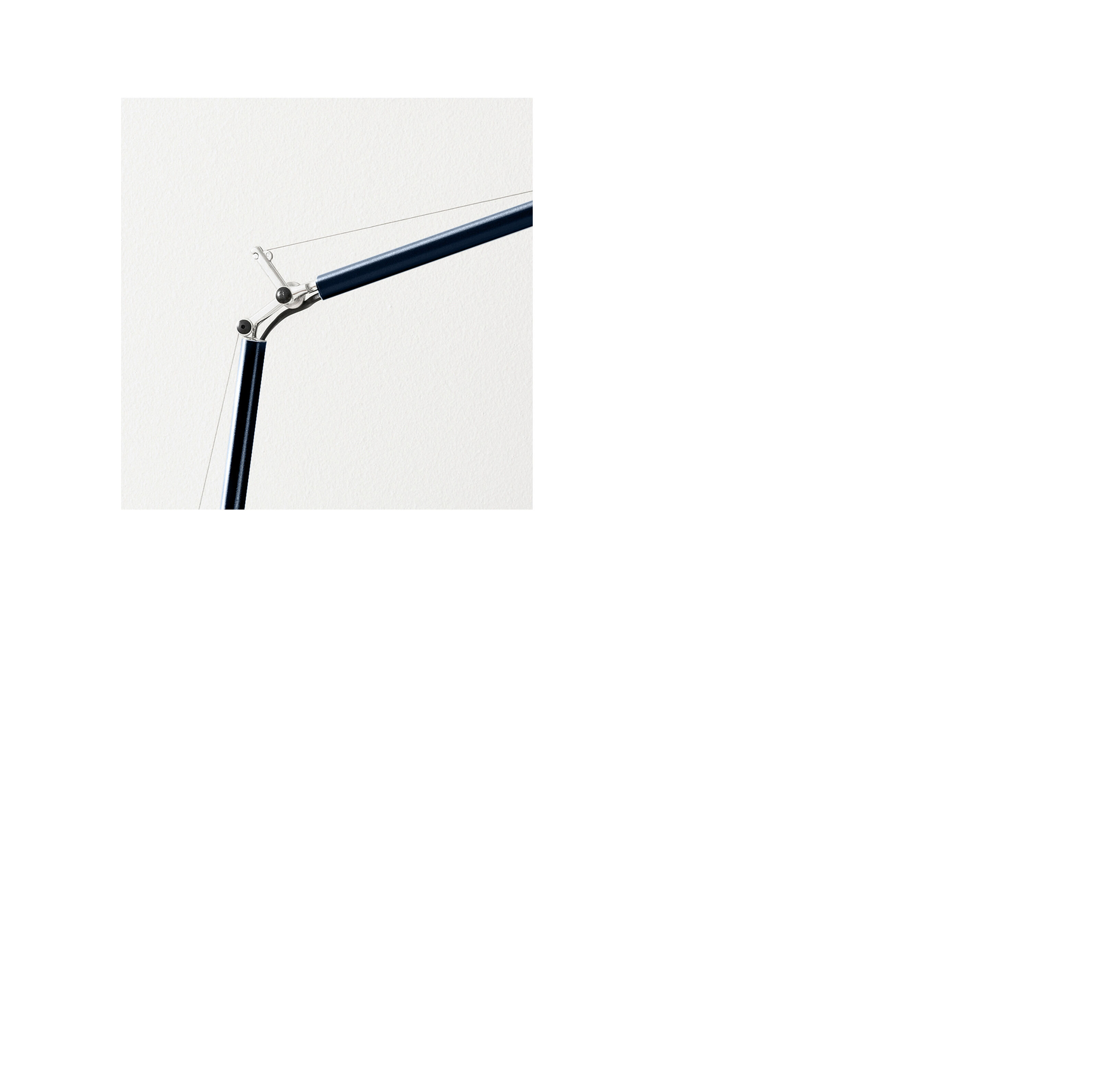 Auf einem hellen Schreibtisch steht eine elegante, dunkelblaue Tischleuchte aus Aluminium mit glänzender Oberfläche. Die Leuchte hat verstellbare silberne Gelenkarme und einen trichterförmigen Lampenschirm. Daneben stehen ein schwarzer Stiftehalter und ein aufgeklappter Laptop mit geöffneter Website.