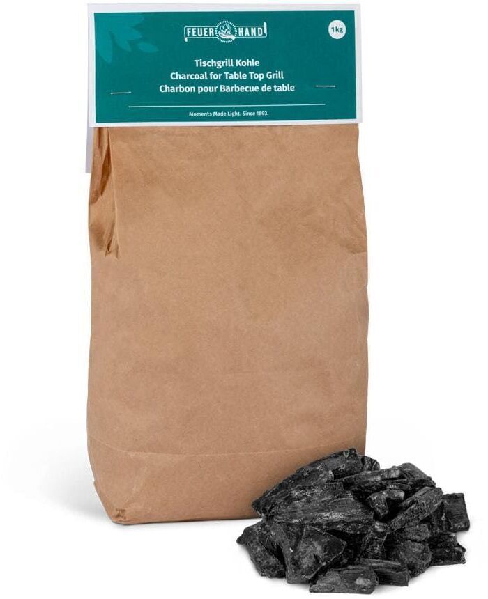 Ein brauner Papierbeutel mit der Aufschrift 'Tischgrill Kohle' und 'Feuer Hand.' Daneben liegen mehrere Stücke von schwarzer Holzkohle.