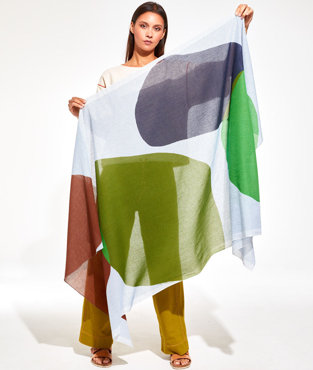 Frau präsentiert leichtes Baumwolltuch 'Galet' mit abstraktem Design in Weiß, Grün, Blau und Braun. Vielseitiges Modeaccessoire für stilvolle Anlässe.