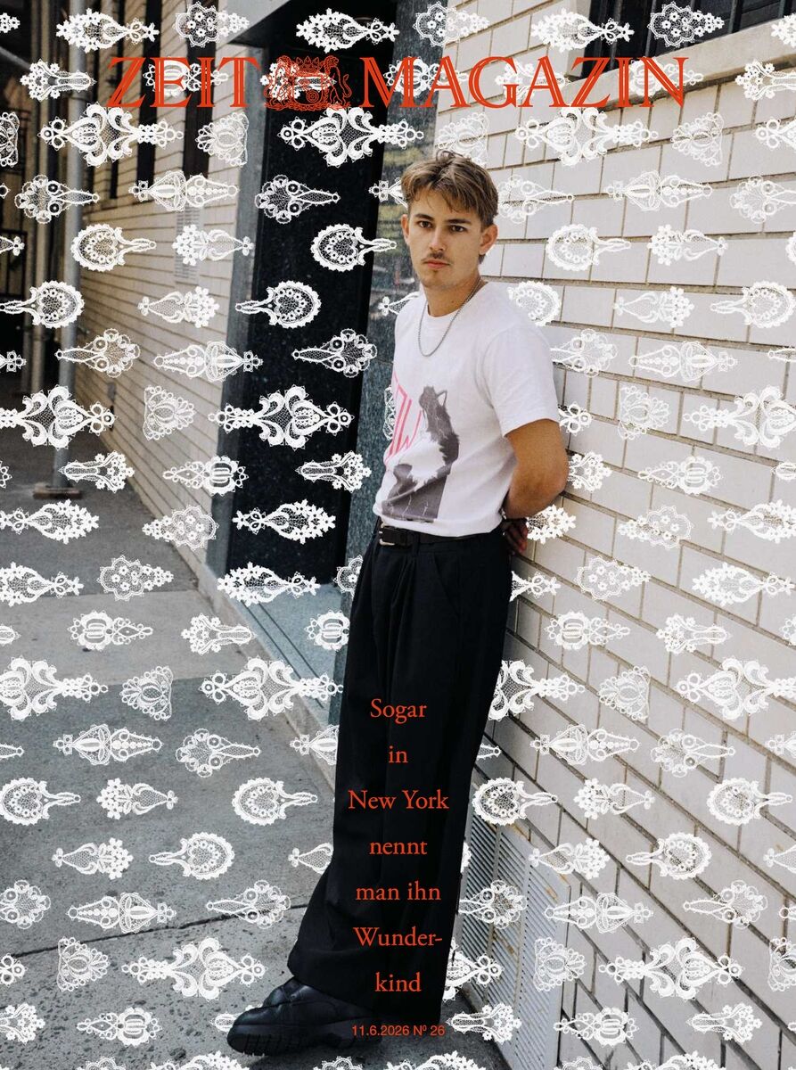 Titelbild des ZEIT Magazins mit einem jungen Mann, der in weißem T-Shirt und schwarzer Hose lässig an einer beigefarbenen Backsteinwand lehnt. Das Cover ist mit weißen Ornamenten überzogen, Titel und Text in Rot. Die Szene wirkt urban und trendbewusst.
