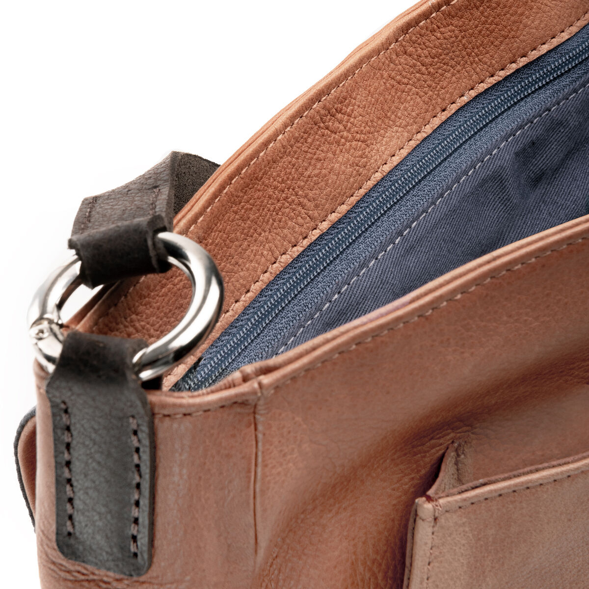 Nahaufnahme einer Slingbag aus Leder mit brauner Außenfläche, schwarzem Schulterriemen und blauen Fächern mit Reißverschluss.