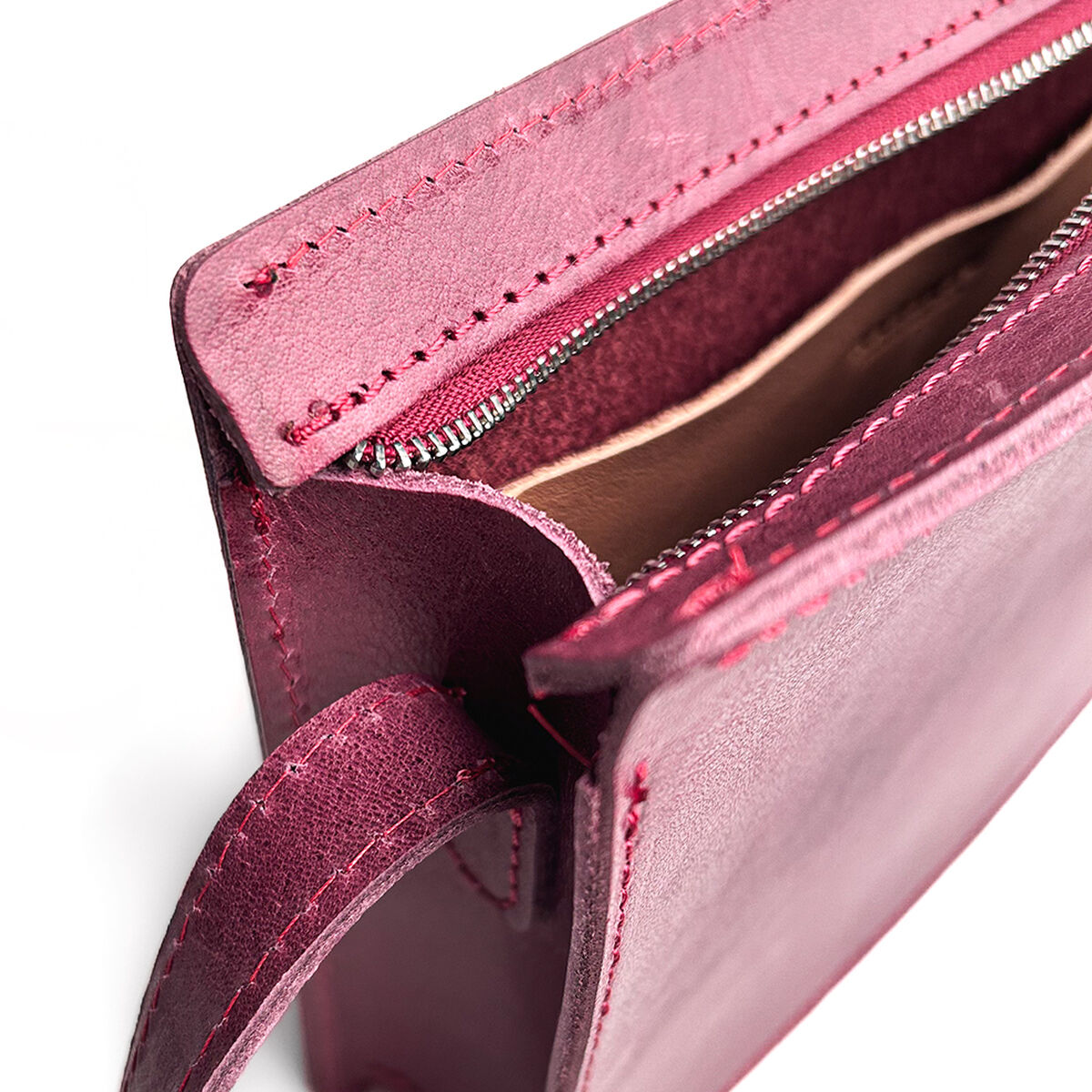 Detailansicht einer glänzenden, pinkfarbenen Kernledertasche mit sichtbarem silbernem Reißverschluss und Innenfach. Die Tasche ist hochwertig verarbeitet und speziell für den täglichen Gebrauch oder als modisches Accessoire für Damen geeignet.