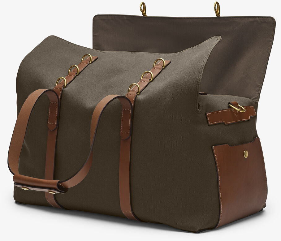 Eine stilvolle Reisetasche »SUPPLY« aus olivgrünem Segeltuch und braunem Leder. Die Tasche hat verstellbare Ledertrageriemen und ist geräumig mit offenen Front- und Innenfächern zu sehen. Ideal für Wochenendtrips und Urlaubsreisen.