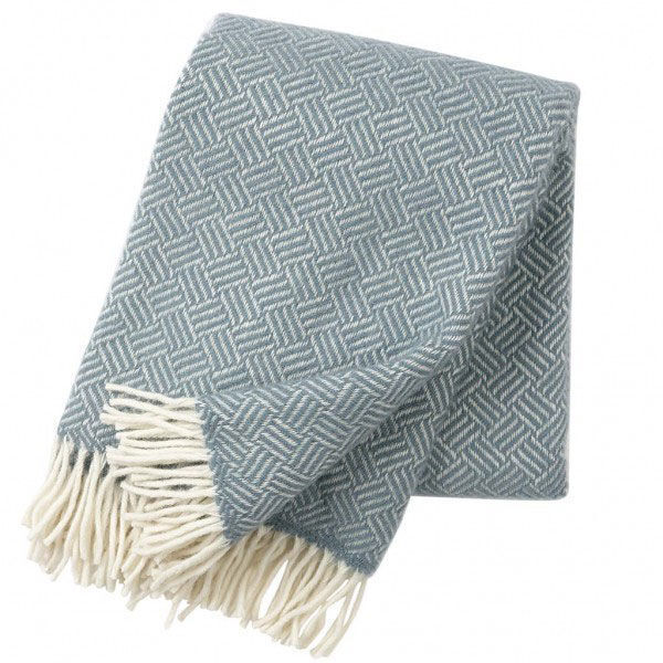 Eine gewebte Decke mit einem blauen und weißen Muster und weißen Fransen an den Enden.