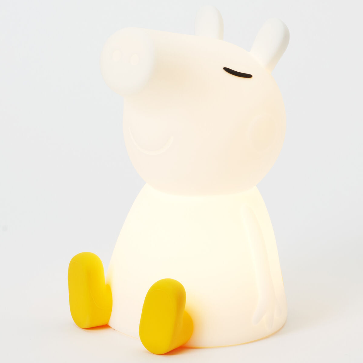 Weißes Nachtlicht in Form von Peppa Pig, einer beliebten Cartoon-Figur, mit gelben Füßen. Die Lampe leuchtet sanft und ist ideal für das Kinderzimmer.