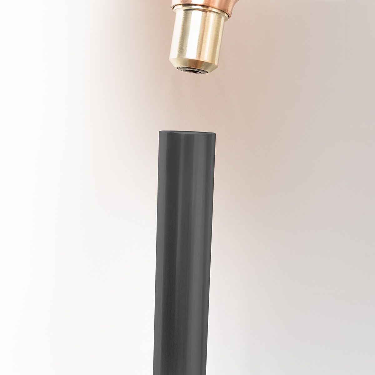 Detailansicht des ZEIT-Sonderedition »Regenmesser Kupfer« von Fischer Manufaktur: Im Vordergrund ein schwarzes pulverbeschichtetes Rohr, darüber die geöffnete, goldglänzende Kupferaufnahme für den regenmessenden Kegel, auf hellem Hintergrund.