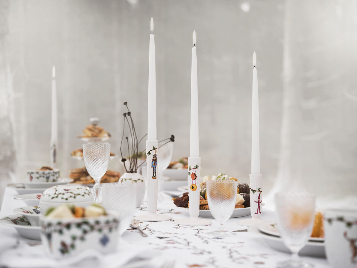 Ein stilvoll dekorierter Tisch mit drei weißen Kerzen in Kerzenständern der Kollektion 'Hammershøi'. Die Szene ist mit Geschirr in zarten Farben und festlichen Motiven ausgestattet. Ideal für elegante und feierliche Anlässe wie Weihnachten oder Hochzeiten.