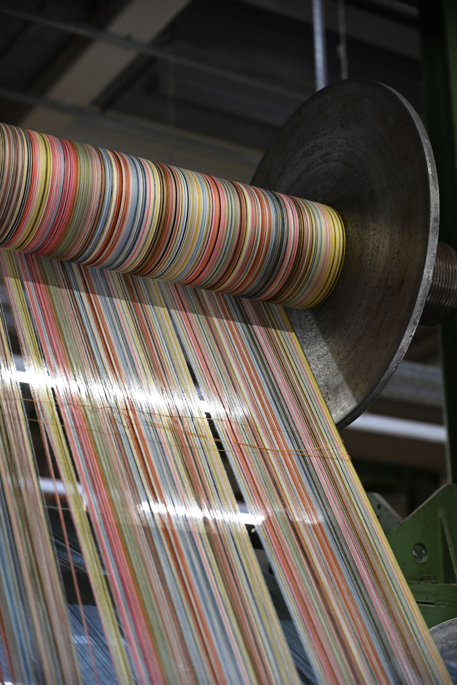 Bunte Fäden auf einer Spule in einer Textilfabrik, die für die Weiterverarbeitung gespannt sind