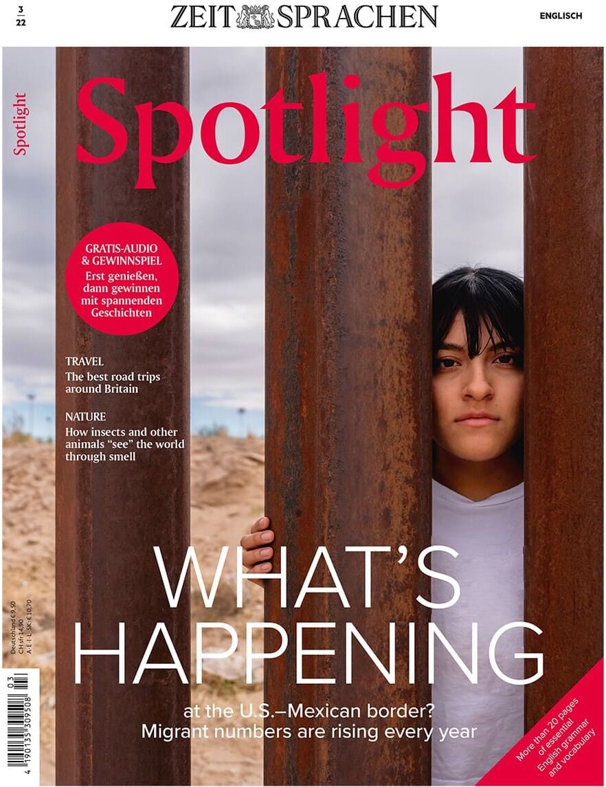 Cover der Zeitschrift Spotlight Heft 03/2022. Eine Frau schaut durch die Spalten eines Grenzzauns zwischen den USA und Mexiko. Der Titel lautet 'WHAT'S HAPPENING at the U.S.–Mexican border?' und thematisiert steigende Migrationszahlen.
