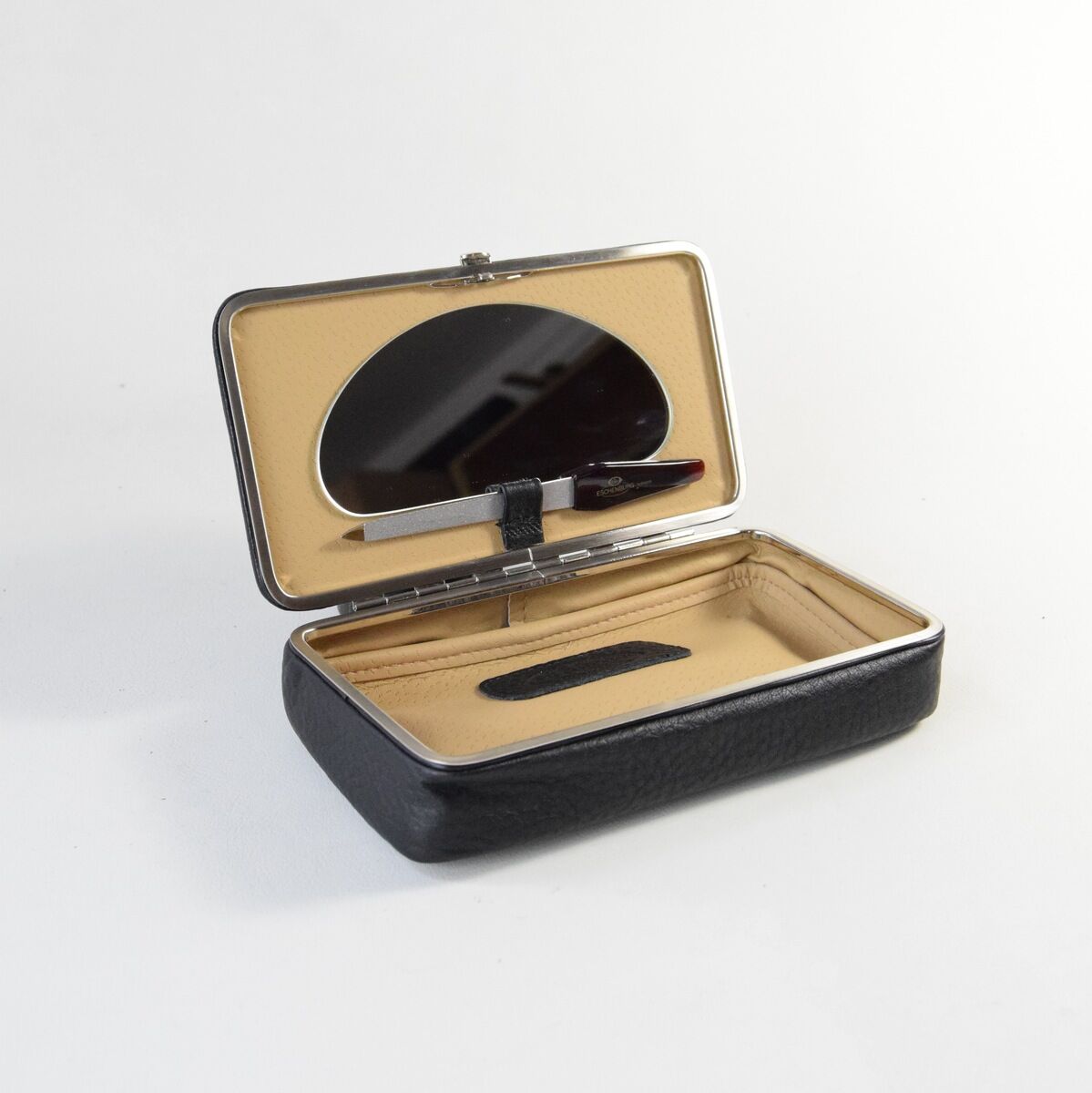 Eine schwarze Utensilienbox aus Leder mit einem beigen Innenraum. Der Deckel der Box ist geöffnet und zeigt eine spiegelnde Fläche im Inneren.