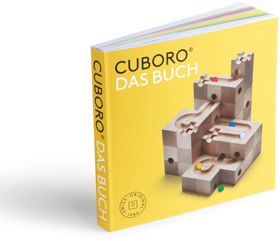 Das Bild zeigt das Buch zur Kugelbahn »CUBORO - DAS BUCH«. Das Cover ist gelb und zeigt eine detaillierte Abbildung einer Kugelbahn aus Holz.