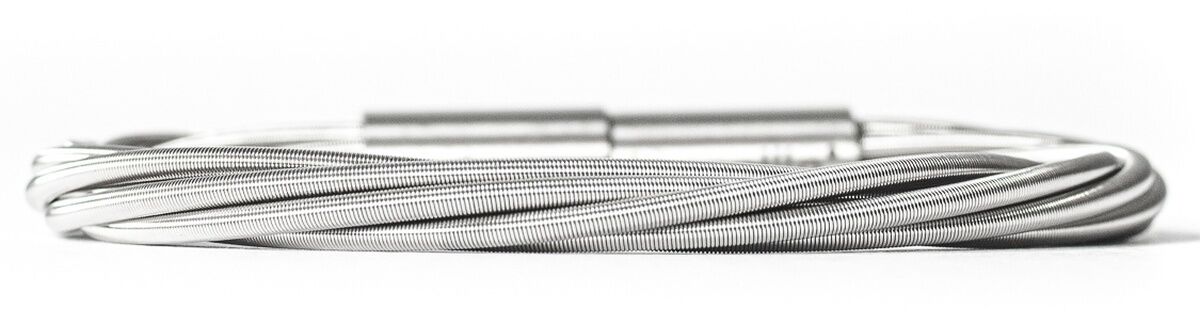 Abgebildet ist ein silberfarbenes Armband im Kabeldesign, das modern und minimalistisch wirkt. Das Schmuckstück besteht aus mehreren dünnen, miteinander gedrehten Metallsträngen und besitzt einen schlichten Schließmechanismus. Das Armband liegt auf weißem Hintergrund.