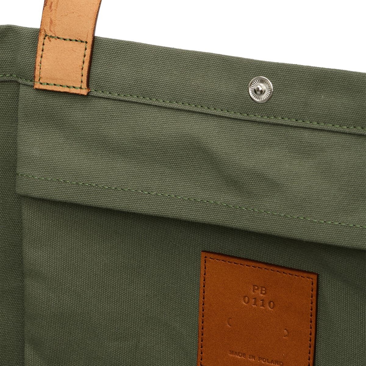 Jubiläums-Markttasche aus grünem Canvas mit braunen Ledergriffen. Die Tasche hat einen Snapverschluss und ein Lederetikett, auf dem steht 'Made in Poland.'