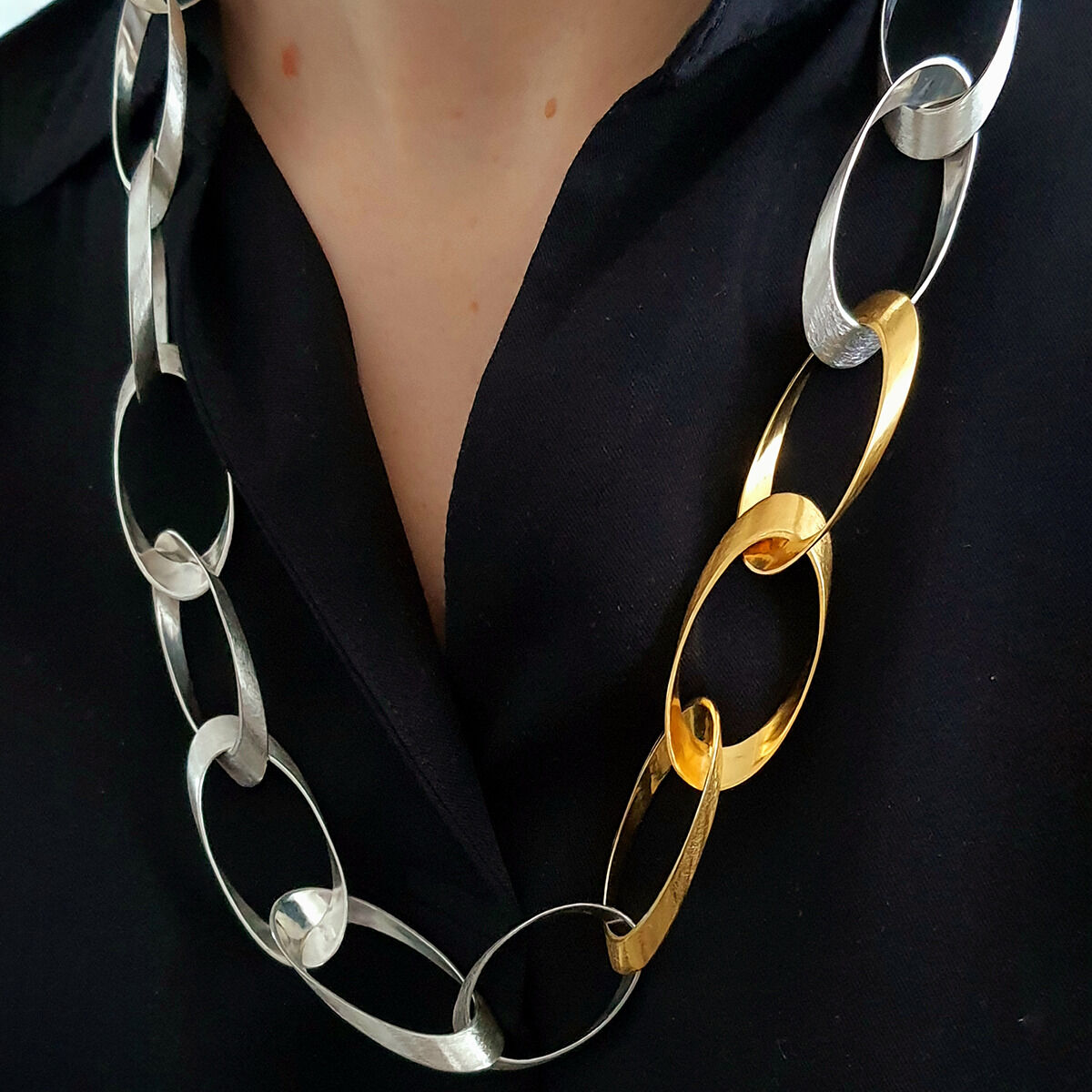 Edles Collier »Standing Ovations« von HML Berlin, vom Berliner Designer Horst Max Lebert. Die Kette besteht aus großen, elliptischen Elementen aus 925er Silber und teilweise feingoldplattiert. Sie wird auf einem schwarzen Hemd präsentiert und wirkt modern, puristisch und hochwertig.
