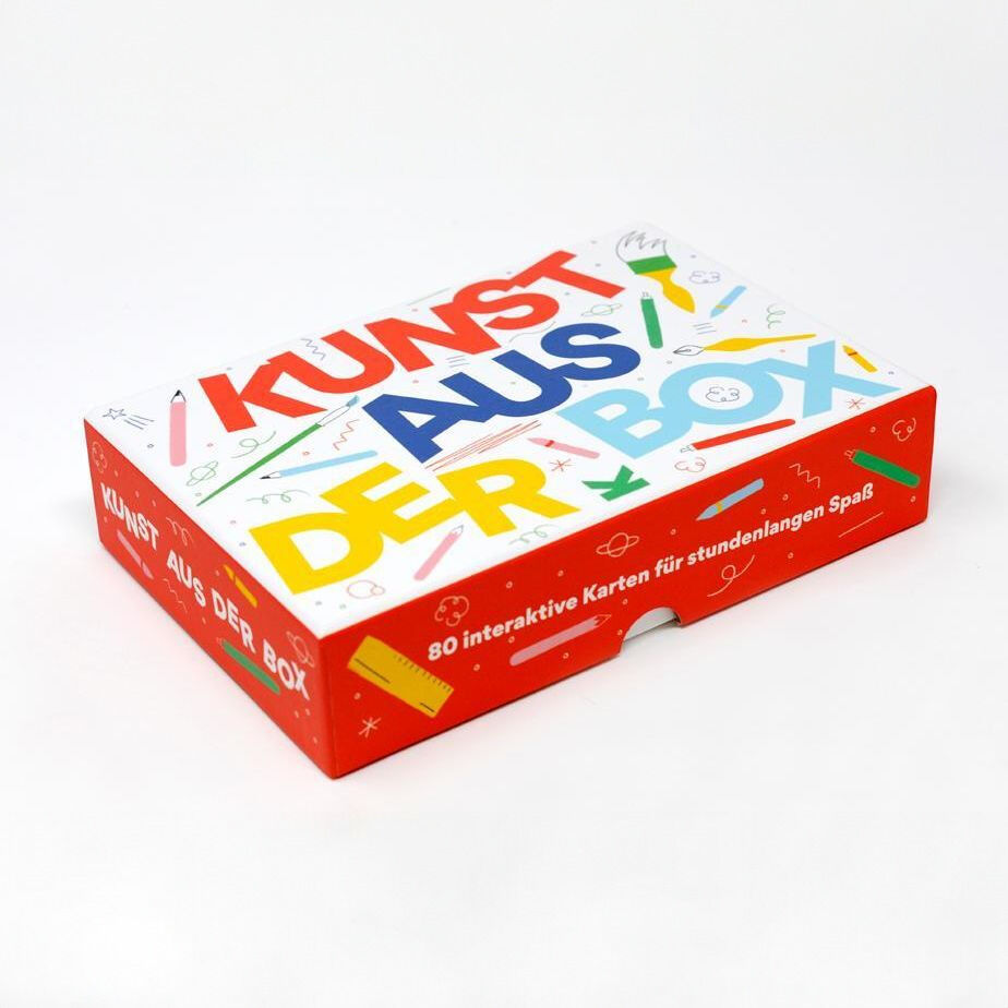 Ein weißer Karton mit der Aufschrift 'Kunst aus der Box' in bunten Buchstaben und kleineren Illustrationen. Die Box enthält 80 interaktive Karten für stundenlangen Spaß.