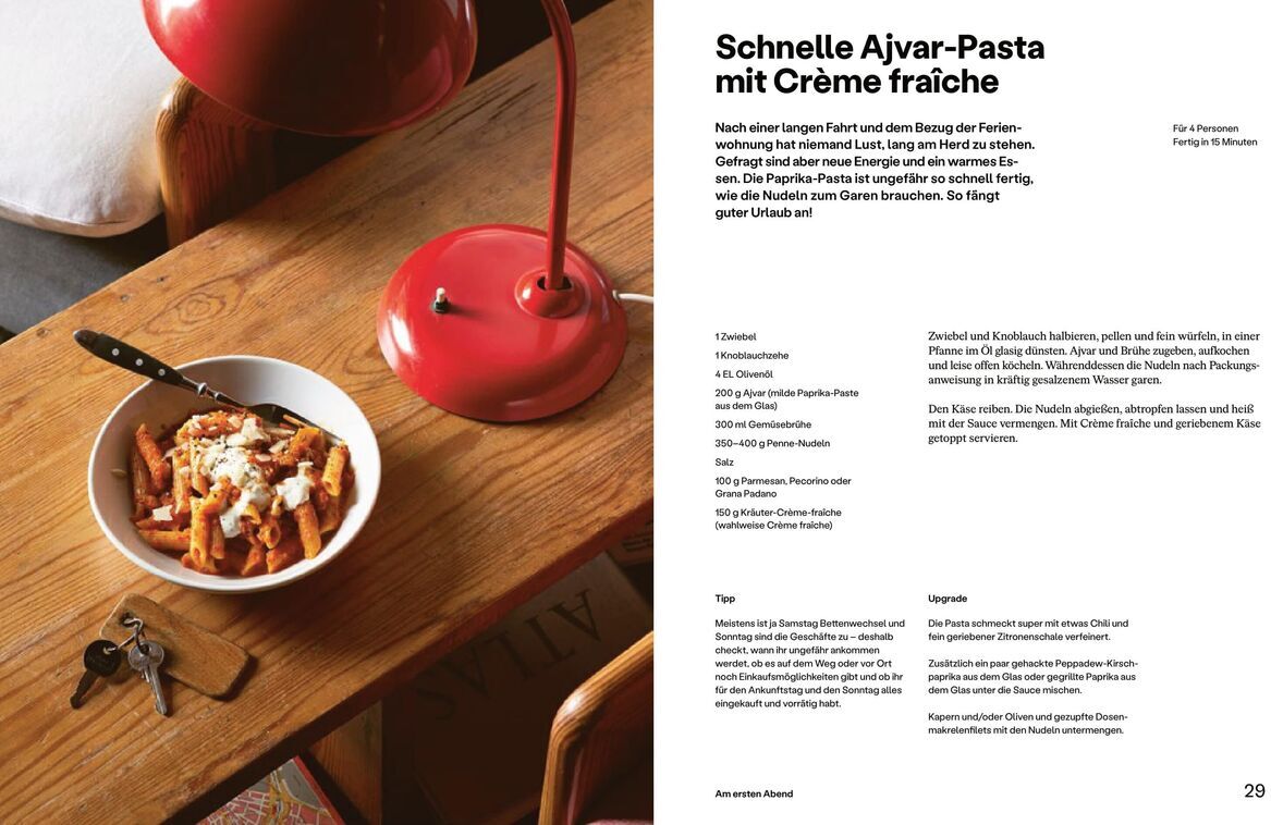 Eine Seite aus dem Buch 'Einfach Urlaub' von Stevan Paul. Auf der Seite ist ein Rezept für Schnelle Ajvar-Pasta mit Crème fraîche abgebildet. Links im Bild steht eine Schüssel mit der fertigen Pasta auf einem Holztisch, daneben liegen ein Schlüsselbund und eine rote Schreibtischlampe.
