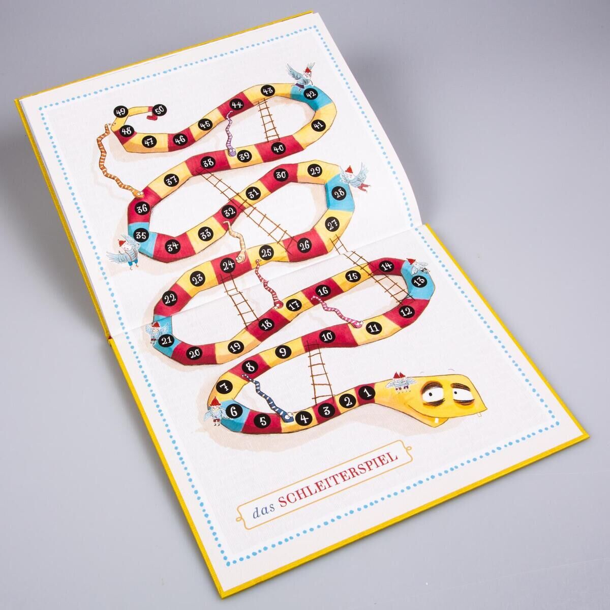 Ein farbenfrohes Brettspiel namens 'Das NEINhorn und die SchLANGEWEILE' mit einer Schlangenabbildung und nummerierten Feldern liegt offen auf einer grauen Oberfläche. Das Spielbrett zeigt eine lustige Schlange mit bunten Feldern und kleinen illustrativen Details.