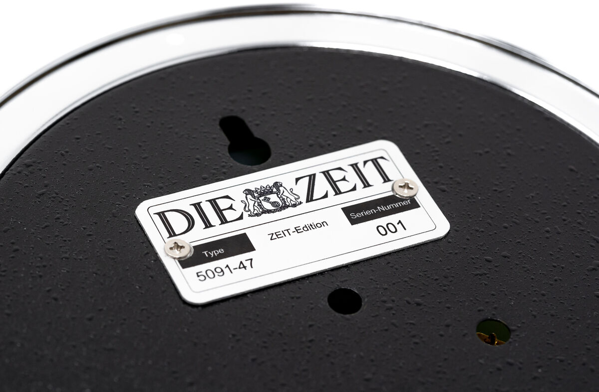 Nahaufnahme eines ZEIT-Sonderedition Raumklimamessers, mit einem schwarzen, strukturierten Hauptgehäuse und silbernen Rand. In der Mitte befindet sich ein Etikett mit der Aufschrift 'DIE ZEIT', darunter die Seriennummer 001.