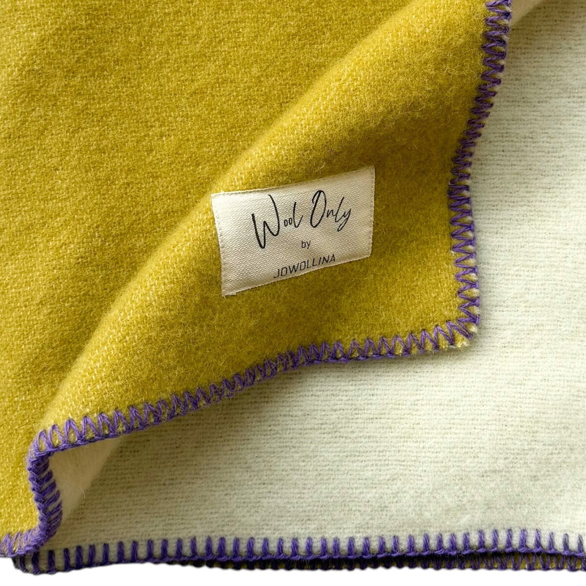 Gelbe und weiße Doubleface-Decke mit lila Randnaht, aus Baumwolle gefertigt. Perfekt für Gemütlichkeit und als Wohnaccessoire geeignet.